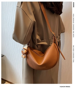 Brown lychee leather saddle bag with gold hardware and plush bear charm on model