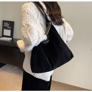 Detail of a large black matte suede hobo bag with leather trim and wide shoulder strap