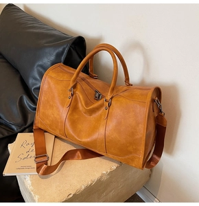 Close-up of vintage brown leather travel bag featuring a sturdy handle and metal hardware