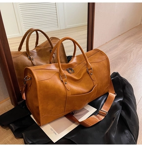 Close-up of large brown vintage travel bag with NOCO logo and adjustable wide strap