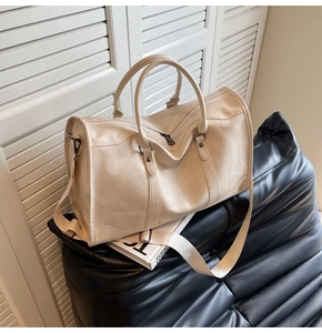 Macro detail of beige lychee textured leather travel bag with metal zipper and strap