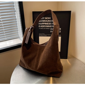 Close-up of deep brown suede tote bag with exposed stitching and vintage brand tag detail