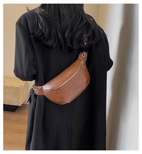 Detail of a brown leather crossbody bag with fashion & bags text on black blazer