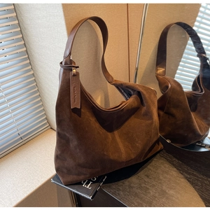 Detail of a vintage dark brown suede tote bag featuring a leather hangtag on the side