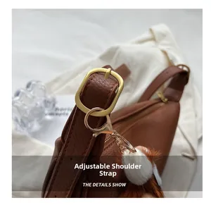 Detail of adjustable synthetic leather strap with gold buckle and plush white pendant