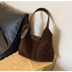 Detailed texture of dark coffee frosted suede tote bag resting on a stone base