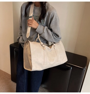 Detail of the adjustable wide shoulder strap and textured cream white travel bag