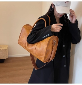 Detail view of large vintage brown leather travel bag with texture and shoulder strap