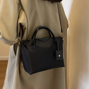Black high-density nylon tote bag with leather handles and mini pouch charm for commuting