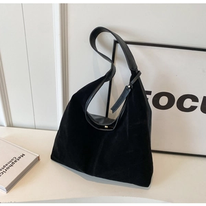 Detail of black suede and smooth leather stitching on a minimalist hobo shoulder bag