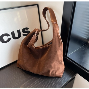 Detail view of large dark brown suede tote bag with leather straps and logo tag