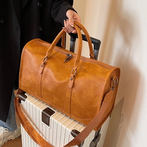 Large vintage brown PU leather travel bag with handles on a white suitcase