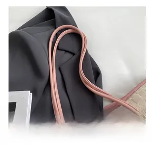 Detail show of cream tote bag with checkerboard embossing and pink shoulder strap