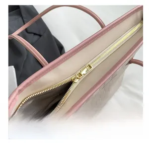 Detail shot of the golden metal zipper and woven texture on a large pink tote bag