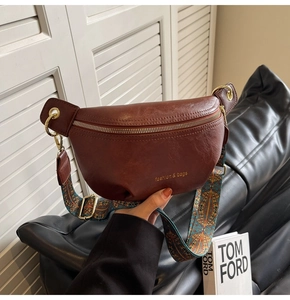 Detail of a brown leather crossbody bag with a colorful ethnic jacquard wide strap