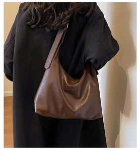 Sac Hobo marron vintage avec large bandoulière et logo de marque porté par un mannequin