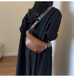 Brown faux leather crescent waist bag featuring a blue ethnic embroidered wide strap