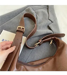 Détail de la bandoulière réglable et boucle en métal doré sur le sac fourre-tout brun