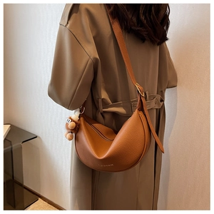 Detail of brown pebbled leather crescent moon bag with fashion text and plush charm