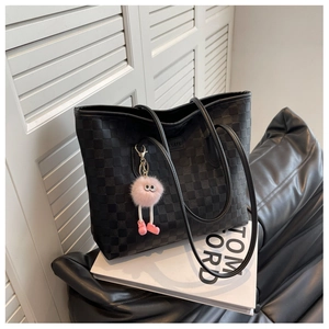 Close-up of black checkered tote bag with pink plush charm on Tom Ford book prop