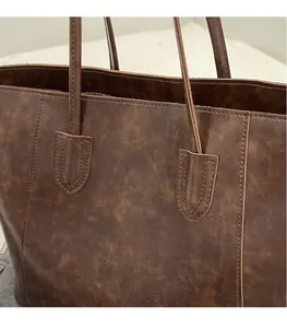 Close-up of brown vintage leather tote bag showing detailed stitching and handle craftsmanship