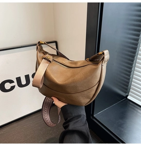 Detail of a brown hobo bag with wide geometric strap and smooth leather texture