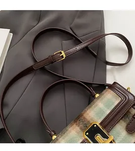 Close-up of adjustable leather shoulder strap and woven tweed texture on a small square bag