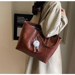 Close-up of retro brown tote bag with leather texture and cute plush charm pendant