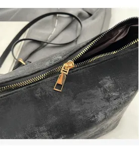 Détail de la fermeture éclair dorée et texture mate noire sur ce sac bandoulière rétro