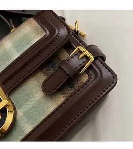 Detail of brown leather stitching and green wool texture with gold metal hardware