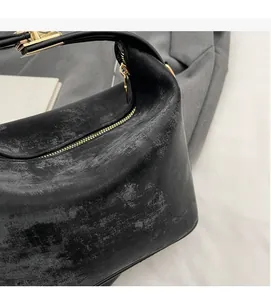 Gros plan sur la texture cuir vintage mat et le zip doré d'un sac à main noir élégant