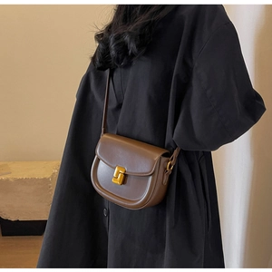 Dettaglio di una borsa a tracolla marrone scuro con finitura opaca e fibbia dorata