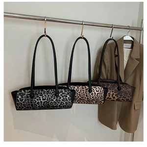 Three leopard print underarm bags in grey and brown shades hanging on a metal rack