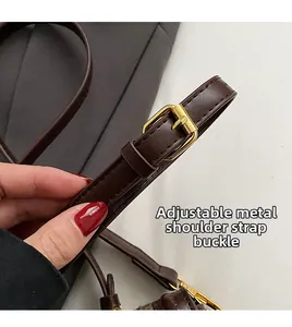 Detailed macro view of adjustable brown leather shoulder strap with gold hardware buckle