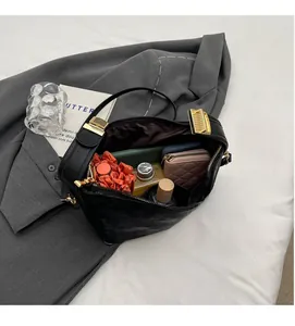 Intérieur spacieux d'un sac à main noir mat contenant portefeuille et cosmétiques