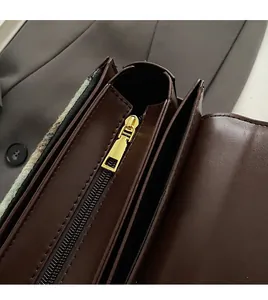 Close-up of smooth gold zipper and neat stitching on dark brown leather handbag