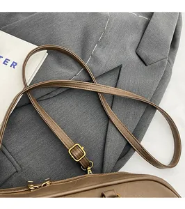 Detail of adjustable slim leather shoulder strap with golden metal buckle on brown handbag