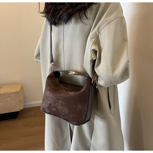 Vue détaillée du sac à main vintage marron foncé montrant la texture vieillie et la ferrure