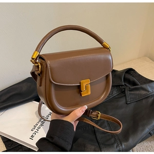 Dettaglio borsa a sella marrone scuro con elegante fibbia a S dorata e pelle sintetica liscia
