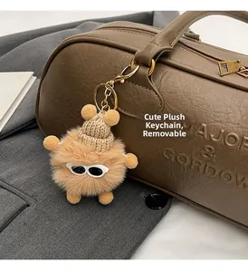 Detail of cute brown plush monster pendant with tiny sunglasses on a leather handbag
