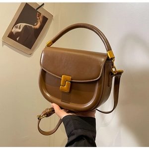 Dettaglio della borsa a sella marrone vintage in pelle lucida e fibbia dorata