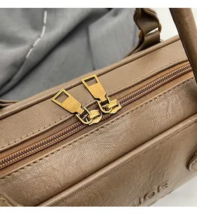 Close-up of smooth dual metal zippers on vintage brown lychee grain leather handbag