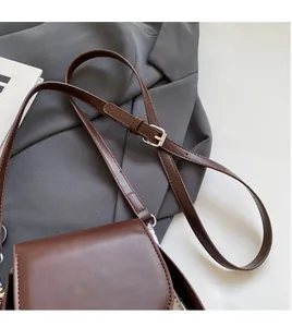 Detail of vintage brown leather crossbody bag featuring adjustable strap and silver buckle