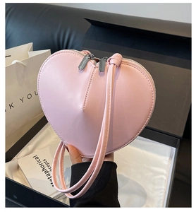 Dettaglio della borsa a cuore in pelle rosa con doppia cerniera in una confezione regalo