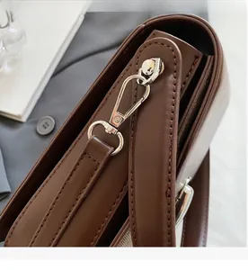 Detail of silver metal buckles and stitching on a vintage dark brown leather crossbody bag