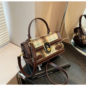 Detailed macro view of the vintage plaid flap and golden twist lock on this stylish handbag