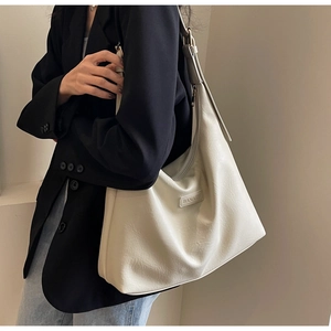 Vue latérale d'un mannequin portant un grand sac cabas beige avec blazer noir et jean
