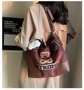 Detail of vintage tote bag featuring teddy bear patch and adjustable leather strap