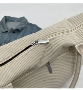 Dettaglio della cerniera argentata e trama in velluto a coste della borsa beige