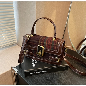 Detail view of vintage crossbody bag featuring brown leather and red-green plaid wool texture